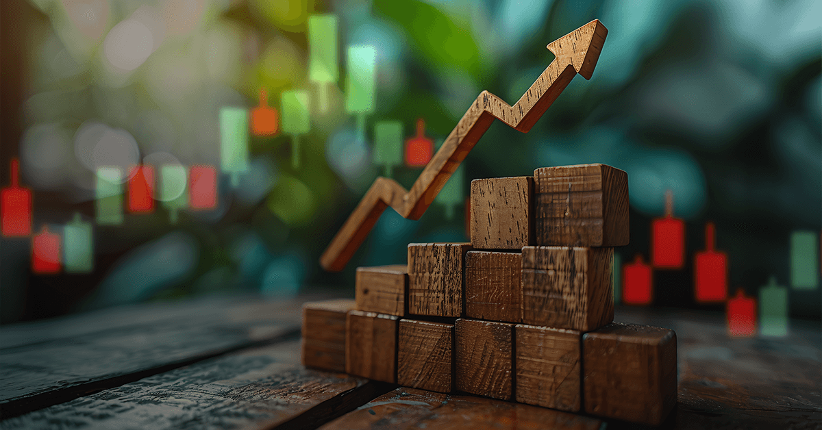 Upward arrow on wooden blocks with stock candles in background, symbolizing financial growth and progress.